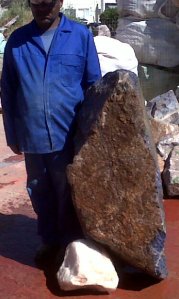 De gevonden steen van 674 kg met een inheemse meneer ernaast om de grote te benadrukken.